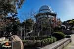 Escultura de la Bola de Newton con la Casa de las Ciencias al fondo