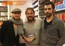 Tres hombres posando con un libro dentro de la Libraría Cartabón
