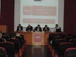Escenario de la sala de conferencias con mesa de ponentes y pantalla