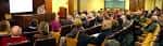 Sala de conferencias con público asistiendo a una presentación