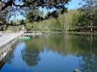 Orilla pavimentada del Lago de Castiñeiras con reflejos de árboles