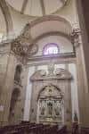 Interior de la iglesia con un altar lateral y una lámpara de araña colgante