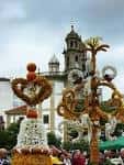 Estructuras florales tradicionales de los Mayos con una iglesia al fondo
