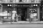 Fachada exterior en blanco y negro de El Café de Macondo con personas en la entrada