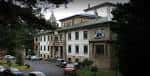 Fachada del edificio histórico del Hospital de Calde rodeado de árboles