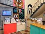 Zona de exposición y escalera en Galería Maraca con murales artísticos