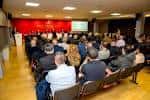 Gran sala de asambleas con público asistente y pantalla de proyección