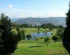 Zona del campo de golf con un lago rodeado de árboles y montañas