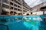 Piscina exterior del hotel con zona de descanso y edificio al fondo