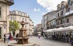 Animada plaza histórica con fuente, terrazas y edificios tradicionales