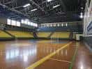 Vista general del pabellón deportivo con gradas amarillas y pista de madera
