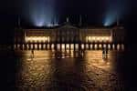 Pazo de Raxoi iluminado por la noche con reflejos en el suelo mojado
