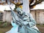 Escultura de un hombre sentado con una bandera en el cementerio