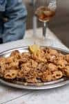 Ración de calamares fritos con limón en un plato metálico