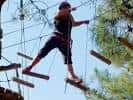 Persona avanzando por un puente de tablones suspendido en el aire