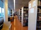 Pasillo interior de la biblioteca con estanterías y mesas de estudio