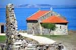 Ermita de La Lanzada junto a restos de la fortaleza y el mar azul