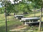 Larga fila de mesas de picnic de piedra en una zona soleada del Parque Forestal de Beade