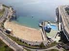 Vista aérea cenital de la Playa de San Amaro y su entorno urbano con piscinas