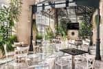 Terraza exterior ajardinada con mesas y sillas para eventos al aire libre