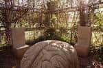 Escultura de mesa y sillas de piedra bajo una pérgola natural