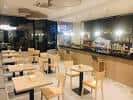 Vista del interior de la cafetería con mesas, sillas y barra.