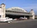 Gran hangar del aeródromo con aviones estacionados en el exterior