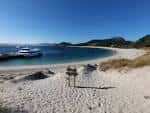 Barco en la playa de las Islas Cíes con señalización de madera