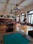 Salón interior del Casino Ferrolano con mesas, sillas y grandes ventanales