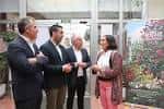 Grupo de adultos conversando en un espacio interior del CEIP Campolongo con un cartel de evento al fondo