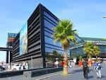 Entrada principal del Centro Comercial A Laxe con palmeras y personas