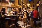 Ambiente nocturno con personas disfrutando en una calle de la Zona de los Vinos