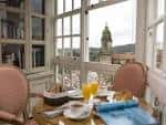Salón acristalado con mesa de desayuno y vistas a la ciudad