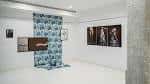Interior de galería de arte con obras y una instalación textil