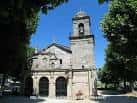 Vista frontal de la Iglesia de Santa Cristina de Lavadores enmarcada por árboles verdes