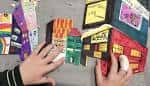 Manos de niños realizando una actividad artística con maquetas de papel