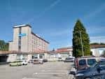 Vista exterior del edificio CIFP Compostela con aparcamiento en un día soleado