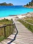Pasarela de madera hacia la playa de Rodas con aguas turquesas