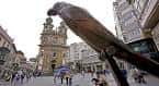 Estatua moderna en una plaza con iglesia barroca al fondo