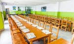 Interior del comedor escolar con largas mesas de madera y sillas, apto para banquetes o reuniones