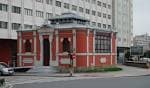 Vista lateral de la Casa del Sol en A Coruña, destacando su fachada roja y el entorno urbano