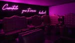 Zona lounge o reservado con sillones tapizados y letrero de neón en el interior de Vanitas