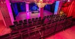 Interior del Ironworks Studios con asientos en filas y escenario iluminado en tonos magenta