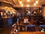Interior del pub con mesas de madera, iluminación ambiental y zona de bar