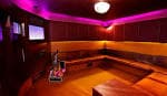 Interior de una sala privada de karaoke con iluminación ambiental magenta y asientos de esquina