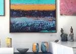 Detalle de una exposición en la galería con pinturas abstractas y objetos de cerámica