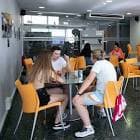 Zona de cafetería o encuentro con mesas y sillas naranjas