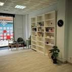 Interior de la sala de la asociación cultural con estanterías y zona de asientos