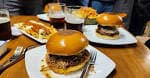 Mesa servida con hamburguesas y bebidas en el restaurante Bode Jatetxea