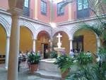 Patio interior porticado con arquerías y fuente central del antiguo Hospital de San Julián